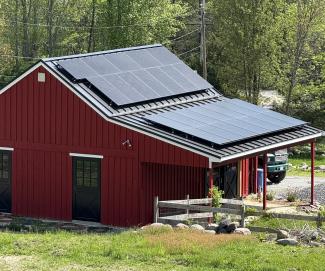 Red barn building at Novena Farms with solar panel array covering southern facing side of the roof.